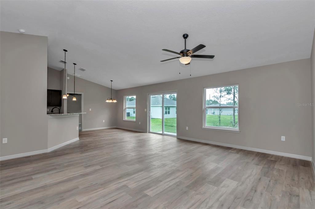 An open-concept living area features wood-look flooring, a ceiling fan, and sliding glass doors — 23465 SW COTTONWOOD LANE, DUNNELLON, FL
