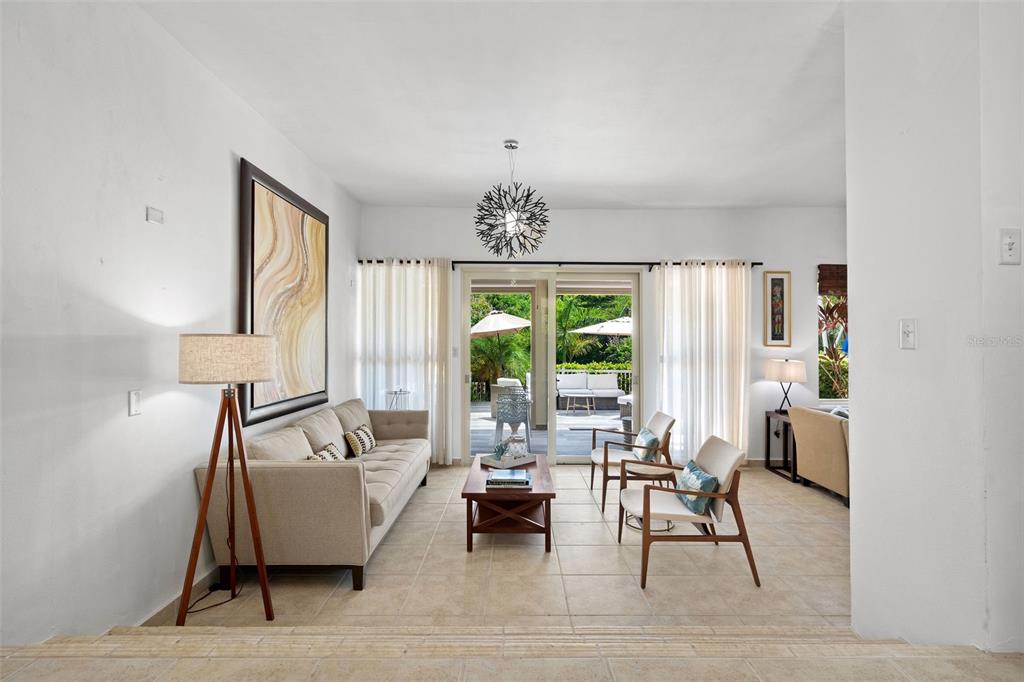 A living room with tile floors, a sofa, two chairs, and a sliding door to a patio — 90 CANDELERO DRIVE UNIT 62, HUMACAO, PR