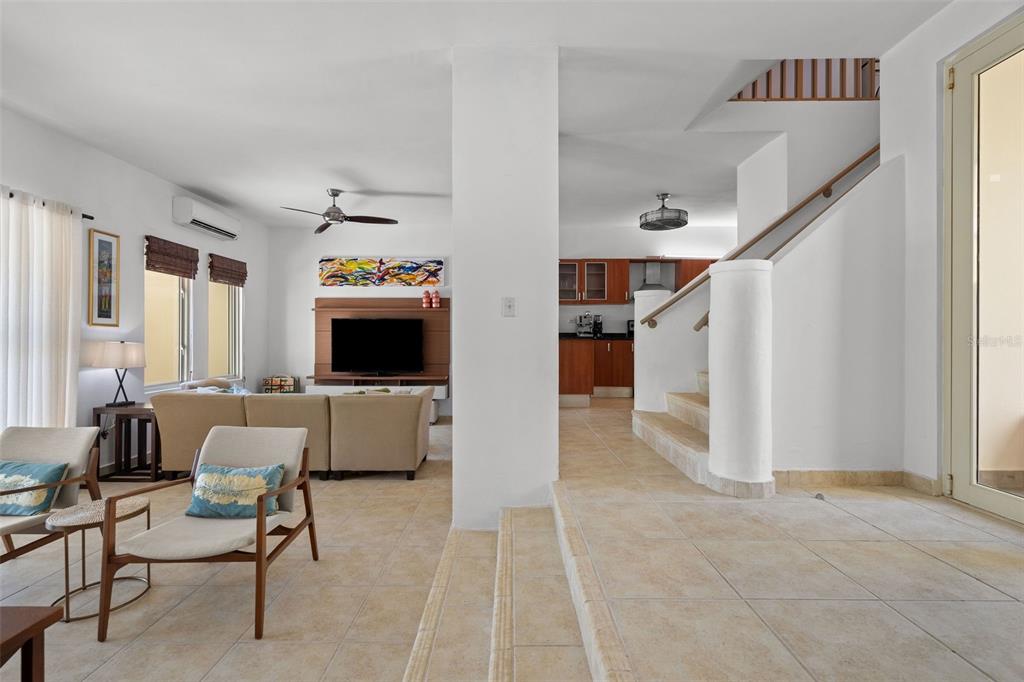 A living room with tile floors, a television, and stairs leading to an upper level — 90 CANDELERO DRIVE UNIT 62, HUMACAO, PR