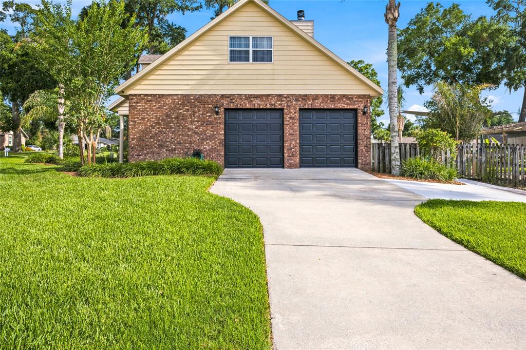A two-car garage with black doors and brick siding stands at the end of a driveway — 3220 SE 21ST AVENUE, OCALA, FL