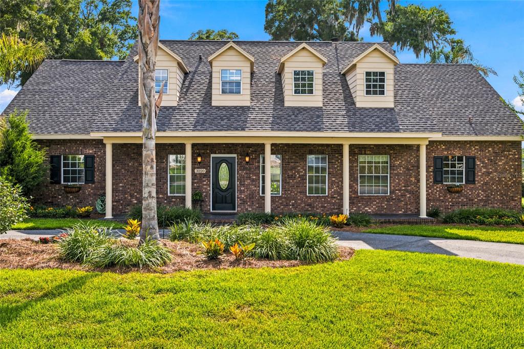A two-story brick house with a covered front porch and four dormer windows — 3220 SE 21ST AVENUE, OCALA, FL