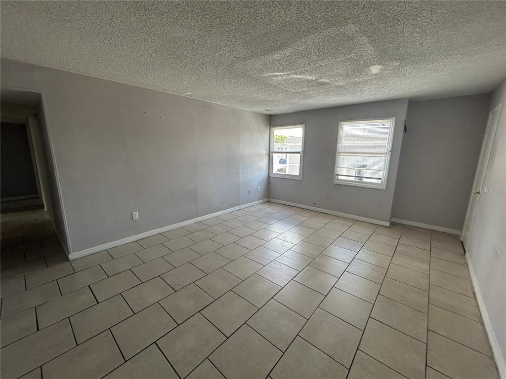 An empty room features gray walls, a textured ceiling, and light-colored rectangular floor tiles — 2773 L B MCLEOD ROAD UNIT 2773D, ORLANDO, FL