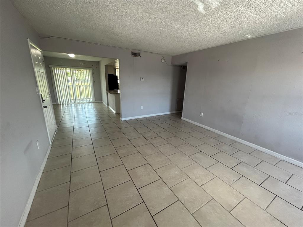 An open living area features light-colored tile flooring, gray walls, and a sliding glass door — 2773 L B MCLEOD ROAD UNIT 2773D, ORLANDO, FL