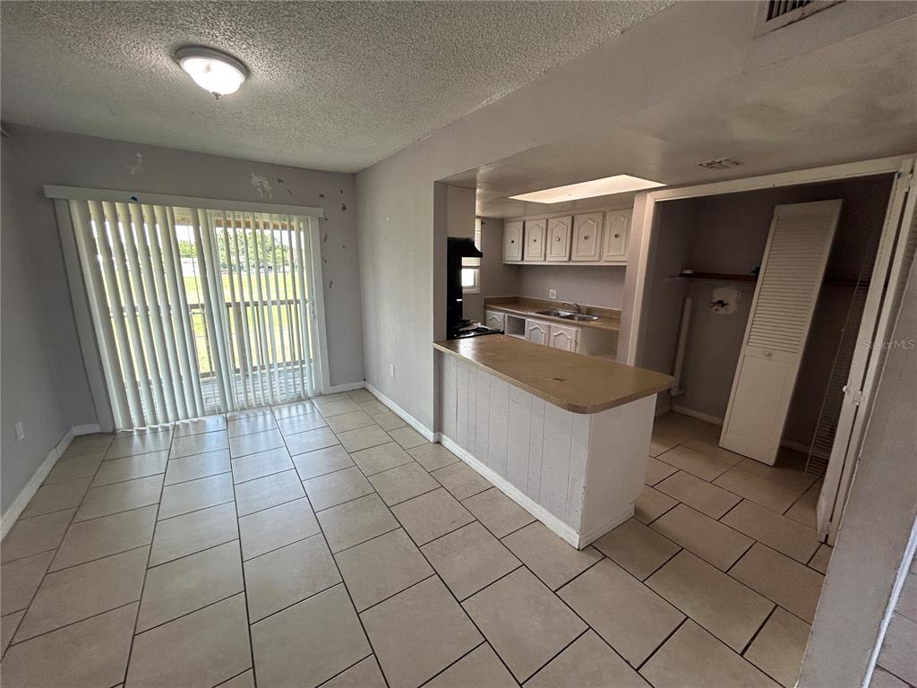 A kitchen with a breakfast bar overlooks a dining area featuring tile floors and sliding doors — 2773 L B MCLEOD ROAD UNIT 2773D, ORLANDO, FL