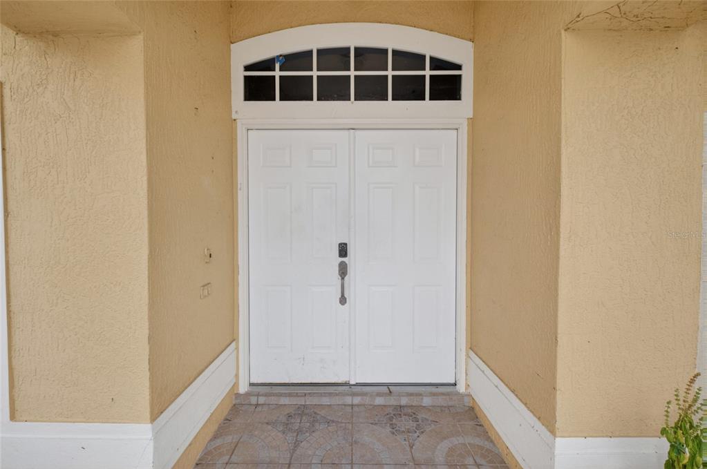 A double white front door with a transom window is set in a stucco entryway — 107 BIANCA COURT, KISSIMMEE, FL