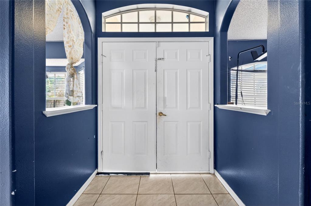 An entryway features white double doors, blue walls, and light-colored tile flooring — 107 BIANCA COURT, KISSIMMEE, FL