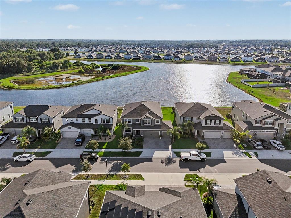 An exterior view of a two-story suburban house with a paved driveway and lake view — 3117 KING FERN DRIVE, WIMAUMA, FL