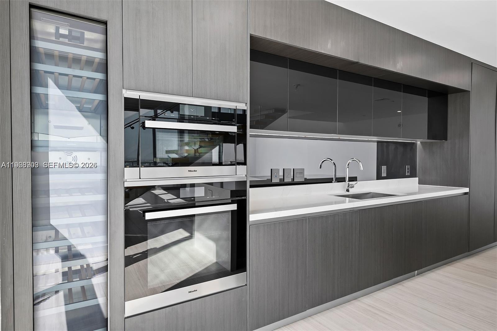 A modern kitchen features dark wood cabinetry, Miele appliances, a wine cooler, and a sink — 851 NE 1st Ave # 5001, Miami FL 33132, MIAMI, FL