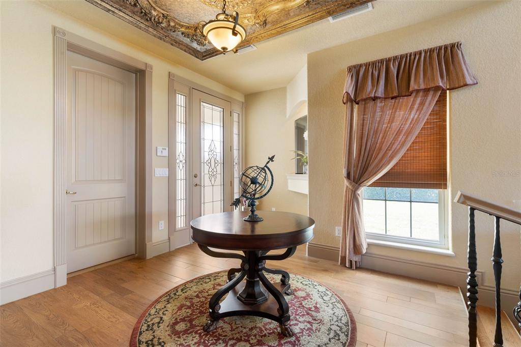 An entryway features a round wooden table, a patterned rug, and an ornate ceiling medallion — 224 YACHT HARBOR DRIVE, PALM COAST, FL