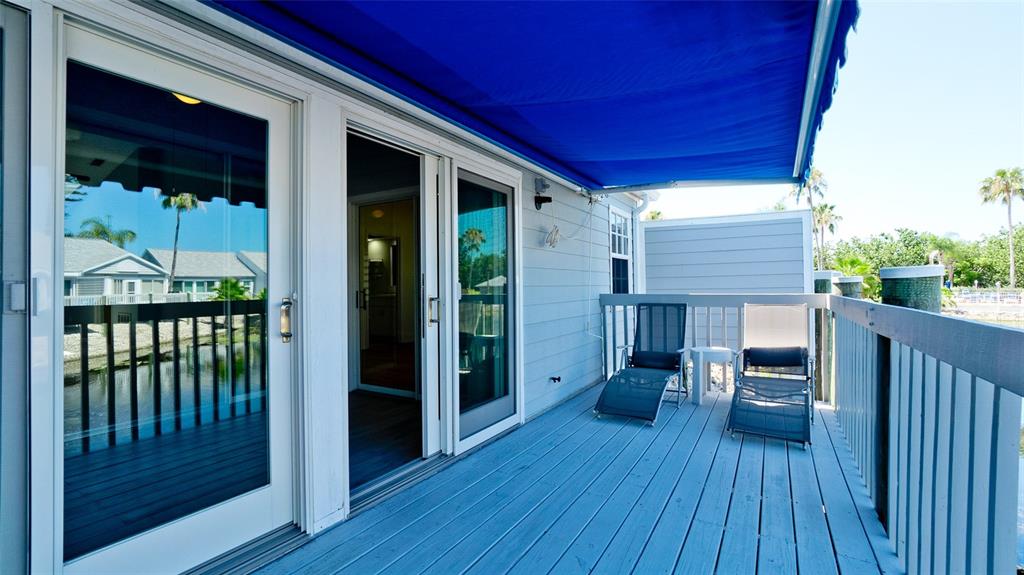 A wooden deck features two lounge chairs under a blue awning overlooking a canal — 506 WOODSTORK CIRCLE, BRADENTON, FL