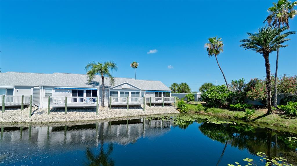 A row of light-colored townhouses with decks overlooks a small pond with lily pads — 506 WOODSTORK CIRCLE, BRADENTON, FL