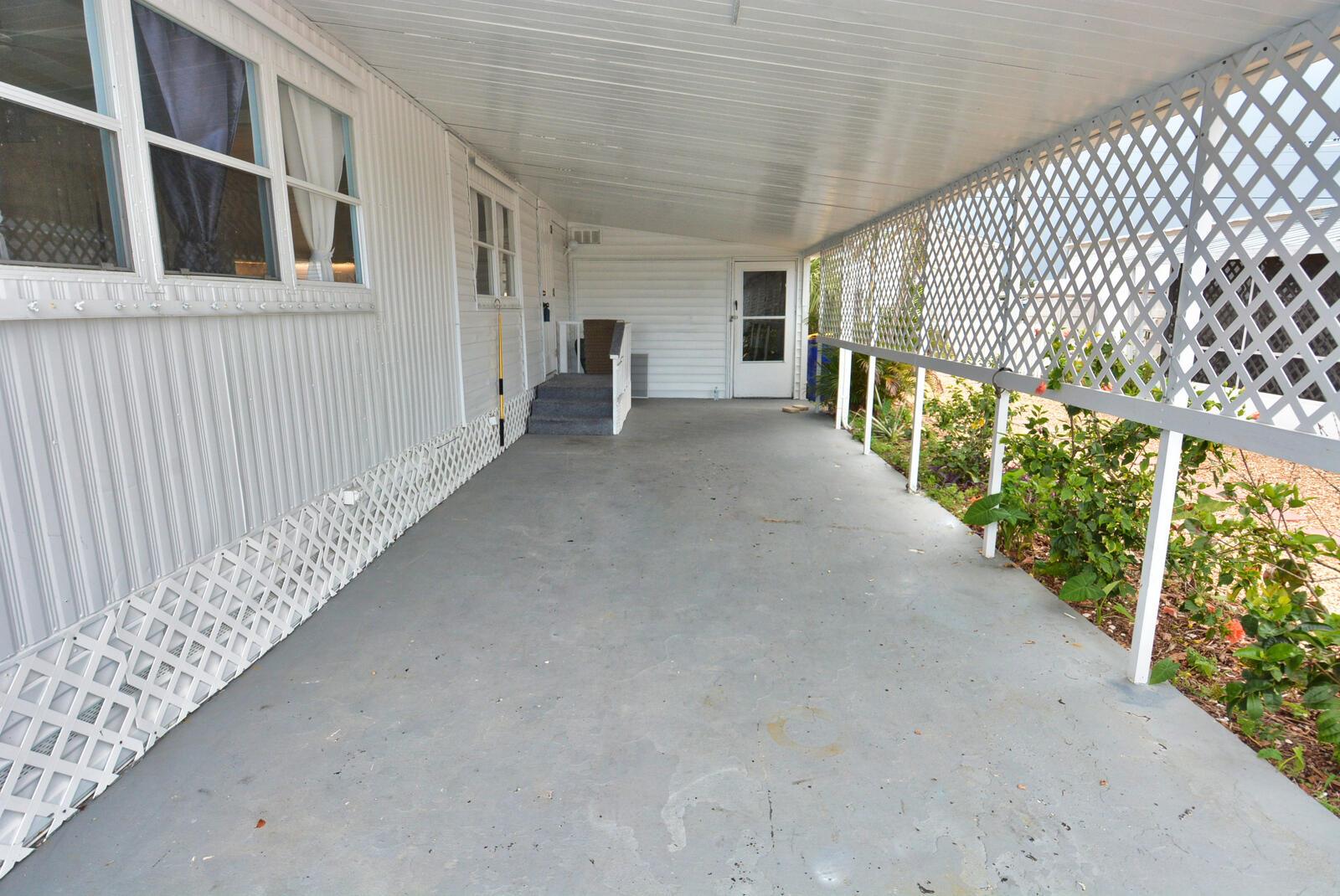 A covered concrete carport features white lattice siding and a set of stairs — 8400 SE Eagle Avenue, Hobe Sound FL 33455, HOBE SOUND, FL