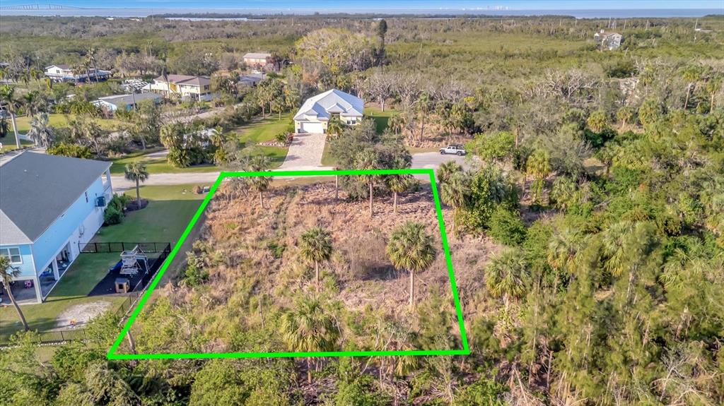 An aerial view shows a vacant, rectangular lot outlined in green next to a house — 1909 KENNEDY COURT, TERRA CEIA, FL