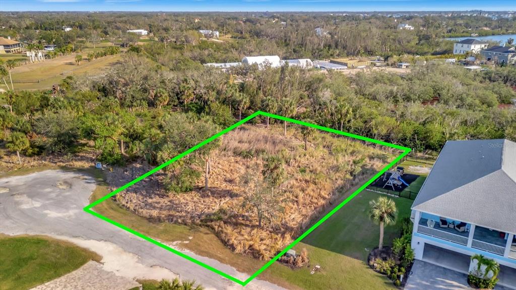 An aerial view shows a vacant, grass-covered residential lot outlined in green next to a house — 1909 KENNEDY COURT, TERRA CEIA, FL