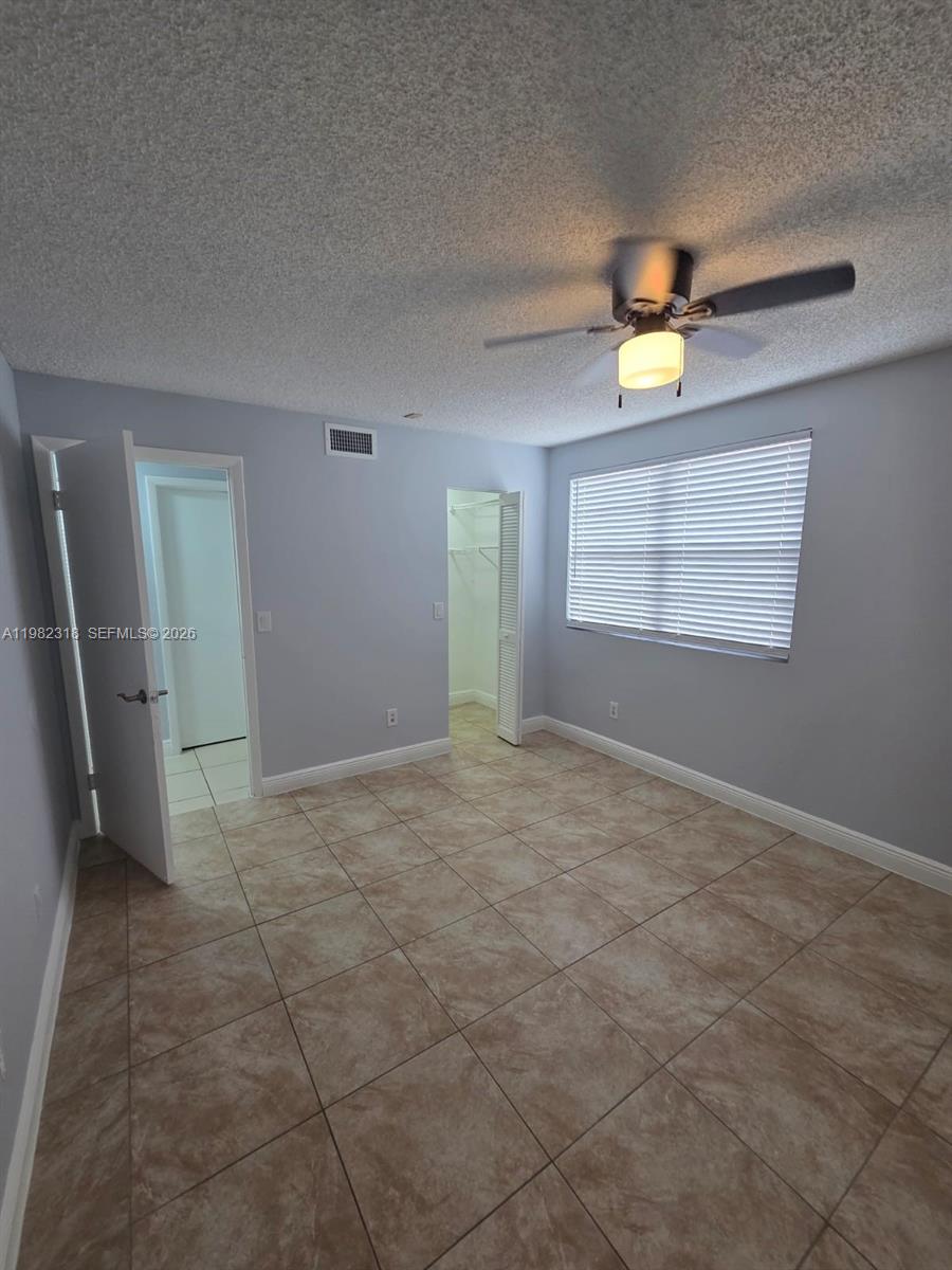 A bedroom features light gray walls, tile flooring, a ceiling fan, and two open doorways — 1241 SW 46th Ave # 1006, Pompano Beach FL 33069, POMPANO BEACH, FL