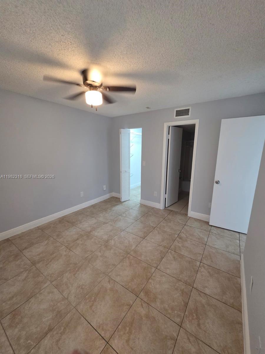 An empty bedroom features light gray walls, beige tile flooring, and a ceiling fan — 1241 SW 46th Ave # 1006, Pompano Beach FL 33069, POMPANO BEACH, FL
