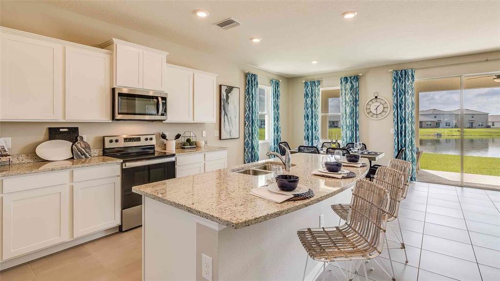 A kitchen with white cabinets, granite countertops, an island, and a view of a lake — 4321 SILVER BIRCH COURT, PALMETTO, FL