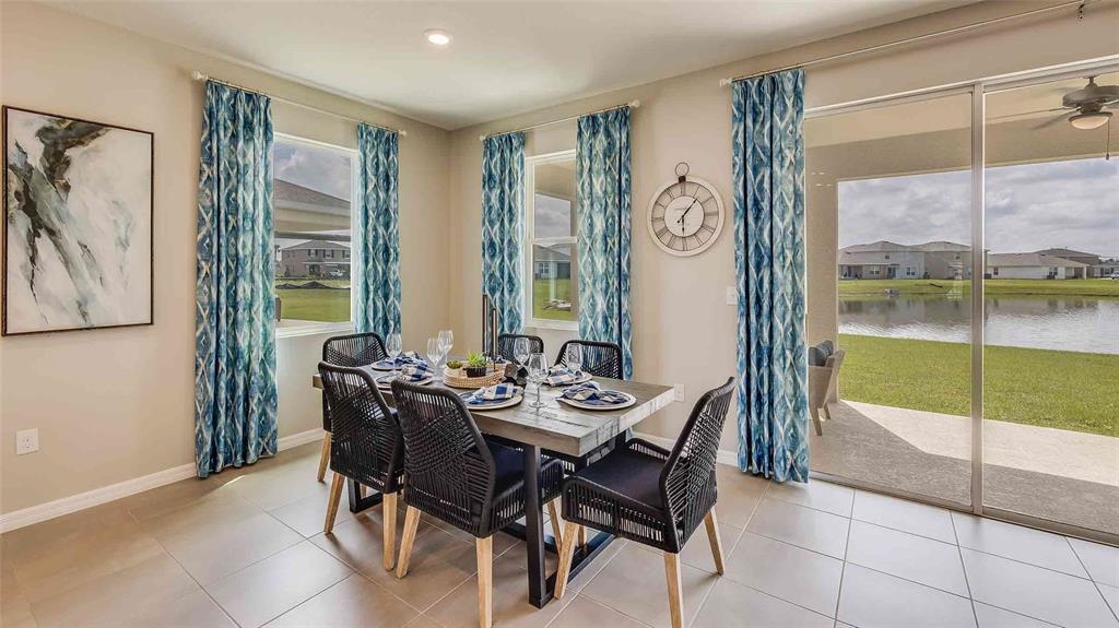 A dining area features a wooden table, black chairs, patterned curtains, and a lake view — 4321 SILVER BIRCH COURT, PALMETTO, FL