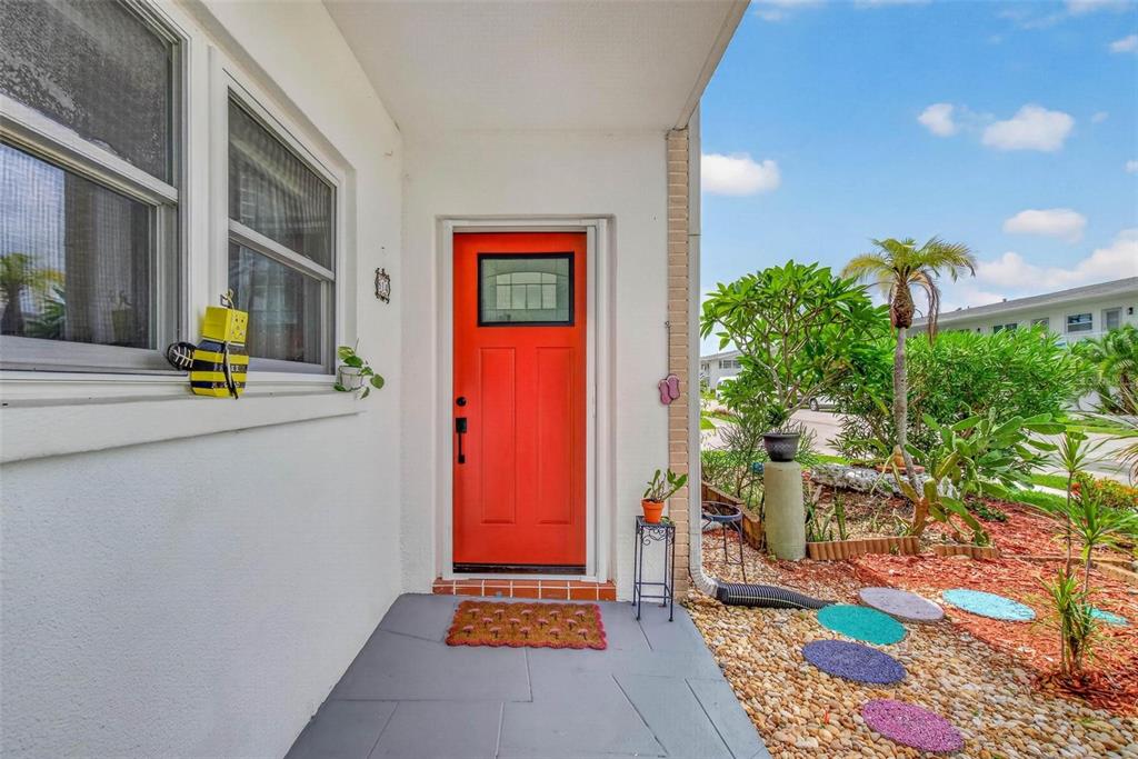 A bright orange front door opens onto a gray patio with a small garden area — 1900 58TH AVENUE N UNIT 14, ST PETERSBURG, FL