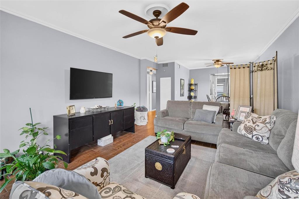 A living room features gray walls, wood-look tile flooring, a ceiling fan, and gray furniture — 1900 58TH AVENUE N UNIT 14, ST PETERSBURG, FL