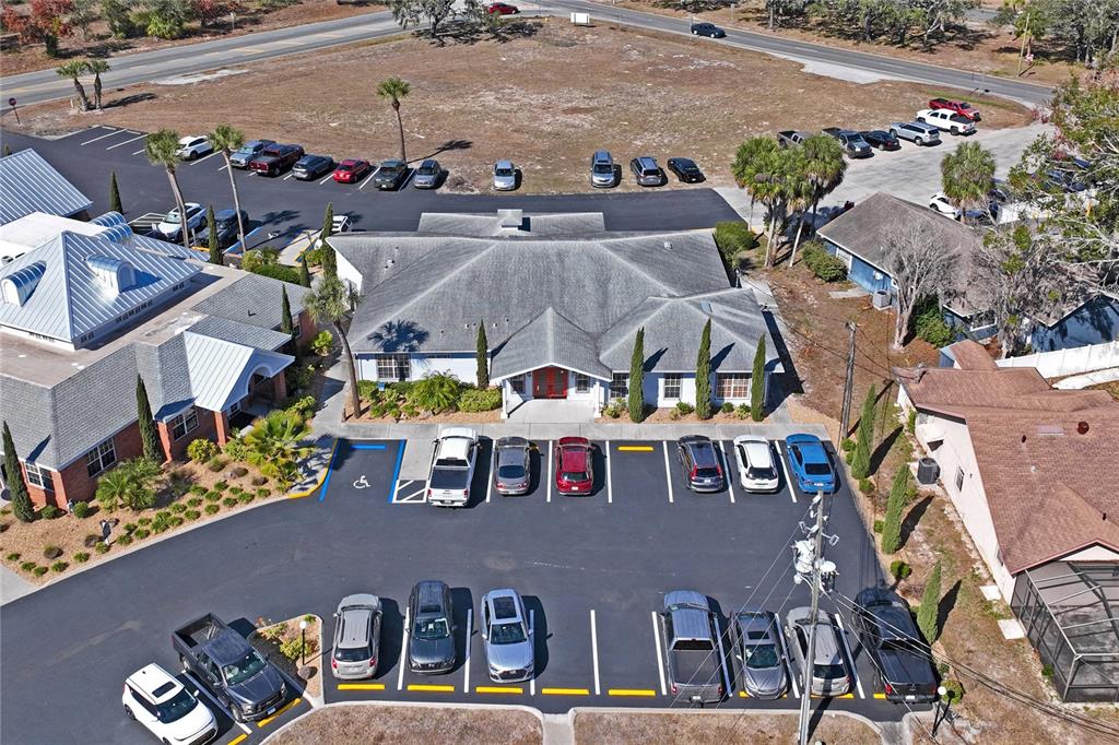An aerial view shows a commercial building with a parking lot and surrounding landscaping — 5300 SPRING HILL DRIVE, SPRING HILL, FL