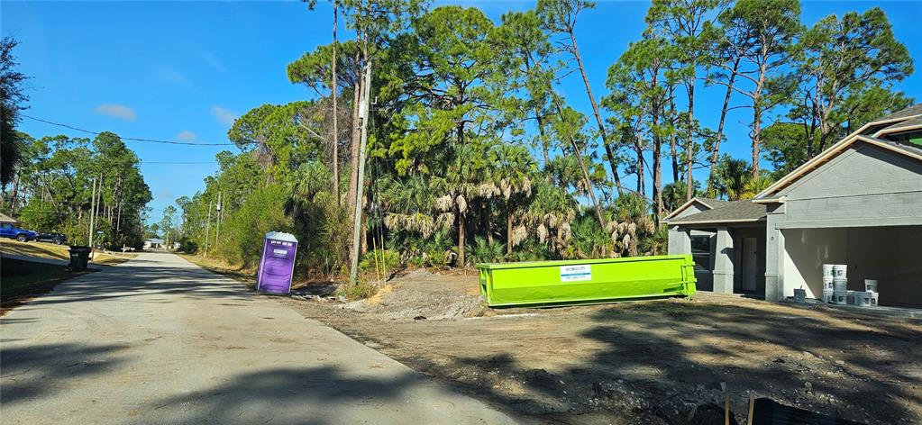 A construction site features a new house, a bright green dumpster, and a portable toilet — STOKIE AVENUE, NORTH PORT, FL