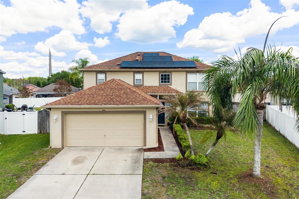 A two-story house features a tan exterior, a two-car garage, and solar panels on the roof — 1915 CORNER CREST COURT, ORLANDO, FL