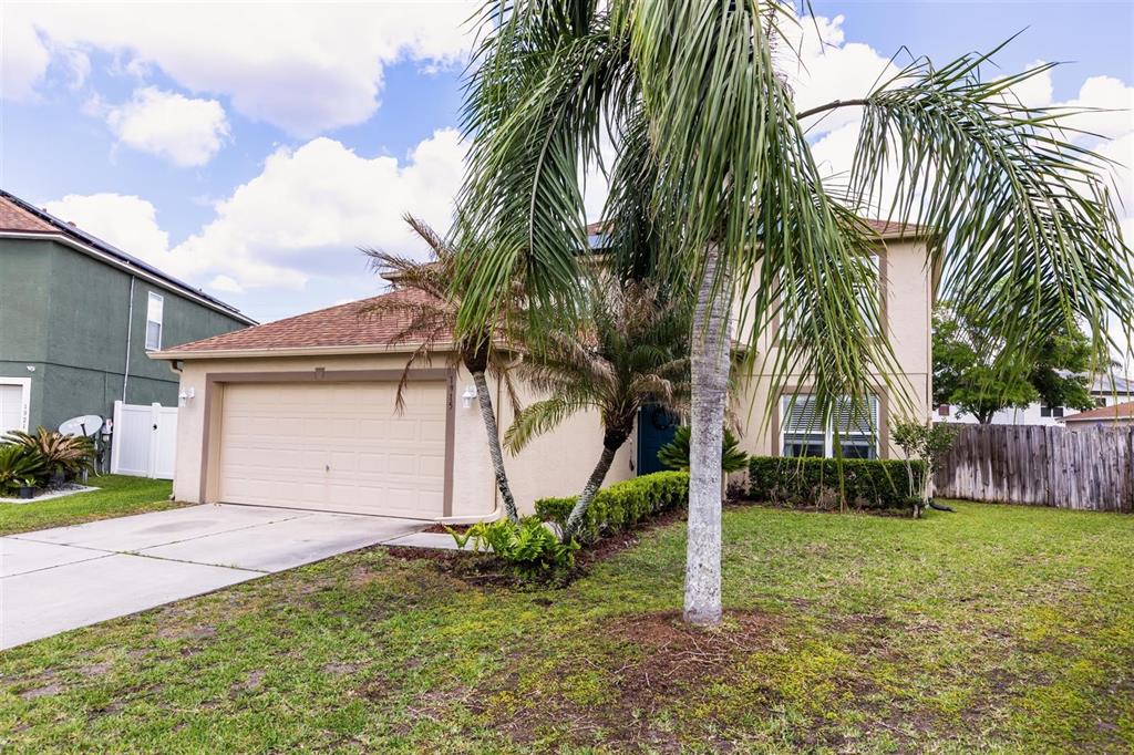 A two-story suburban house with a tan stucco exterior, a two-car garage, and palm trees — 1915 CORNER CREST COURT, ORLANDO, FL