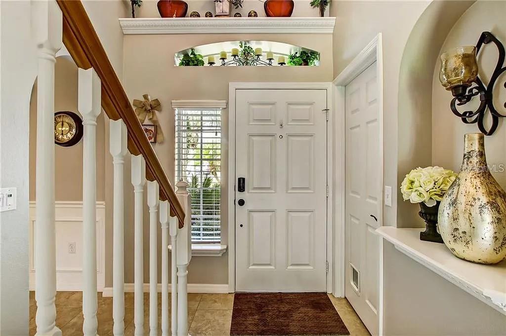 An interior room features beige walls, white wainscoting, tile flooring, and two arched doorways — 1915 CORNER CREST COURT, ORLANDO, FL