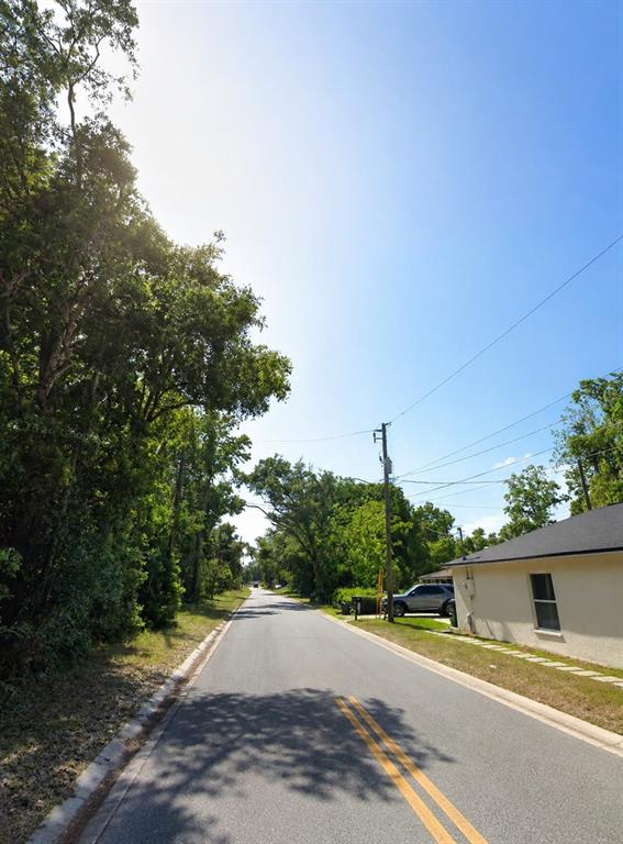 A paved road stretches into the distance, flanked by lush trees and a residential house — 00 BUNGALOW BOULEVARD, SANFORD, FL