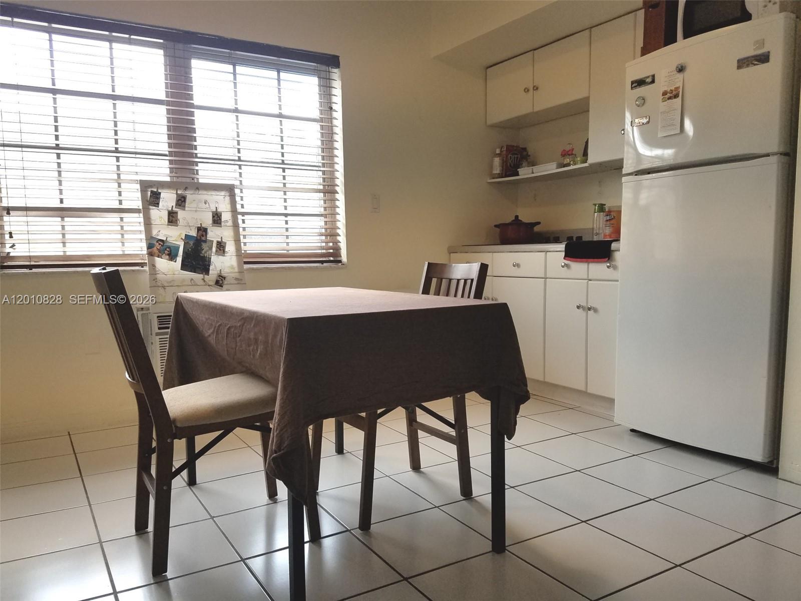 A dining area features a table with a brown cloth, two chairs, and a small kitchen — 6565 Santona St # B8, Coral Gables FL 33146, CORAL GABLES, FL