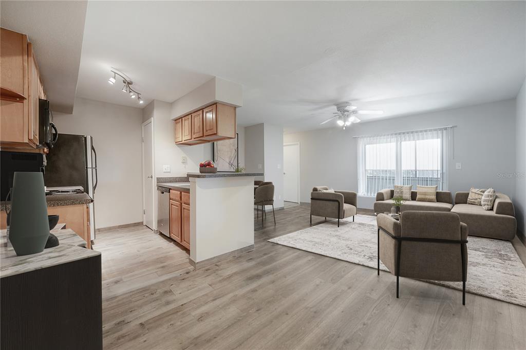 An open-concept kitchen and living area featuring light wood flooring and neutral-toned furniture — 9100 DR MARTIN LUTHER KING JR STREET N UNIT 905, ST PETERSBURG, FL