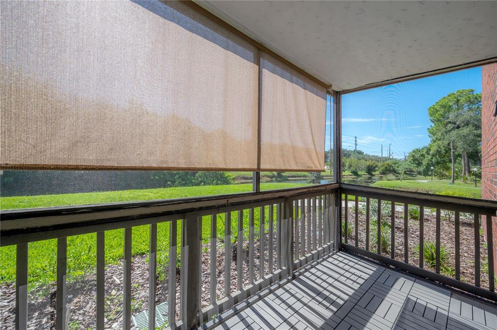 A screened-in porch features a wooden railing, gray deck tiles, and a retractable sun shade — 9100 DR MARTIN LUTHER KING JR STREET N UNIT 905, ST PETERSBURG, FL