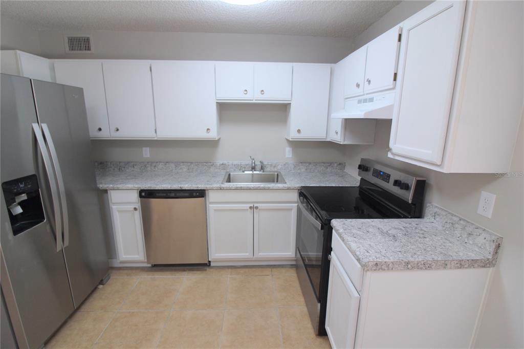 A kitchen with white cabinets, stainless steel appliances, and speckled granite countertops — 5971 NW 11TH PLACE, OCALA, FL