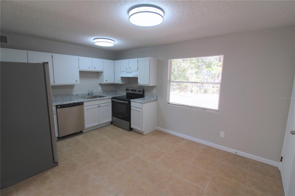 A kitchen with white cabinets, stainless steel appliances, tile flooring, and a window — 5971 NW 11TH PLACE, OCALA, FL