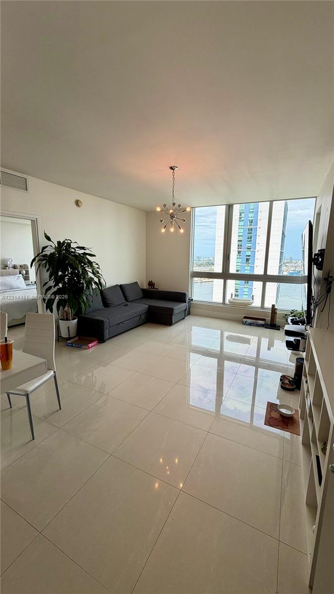A living room with tile floors, a sectional sofa, and floor-to-ceiling windows overlooking water — 300 S Biscayne Blvd # 3212, Miami FL 33131, MIAMI, FL