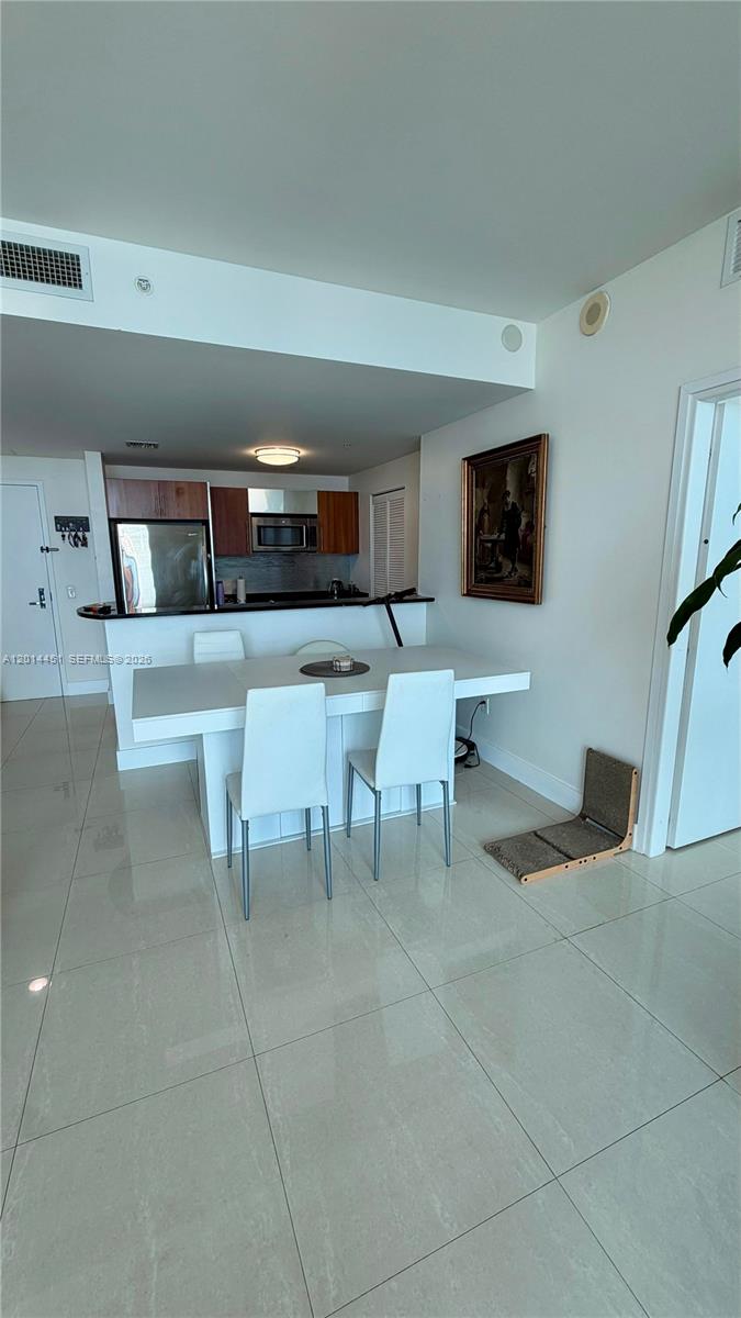 A dining area with a white table and chairs sits in front of an open kitchen — 300 S Biscayne Blvd # 3212, Miami FL 33131, MIAMI, FL