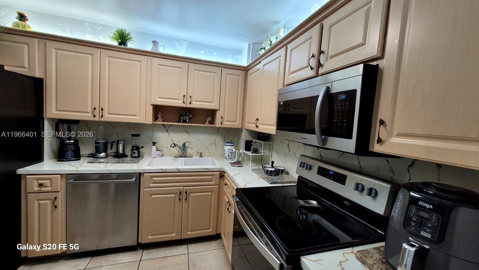 A kitchen features light wood cabinets, stainless steel appliances, and a white marble-patterned backsplash — 4001 Hillcrest Dr # 705, Hollywood FL 33021, HOLLYWOOD, FL