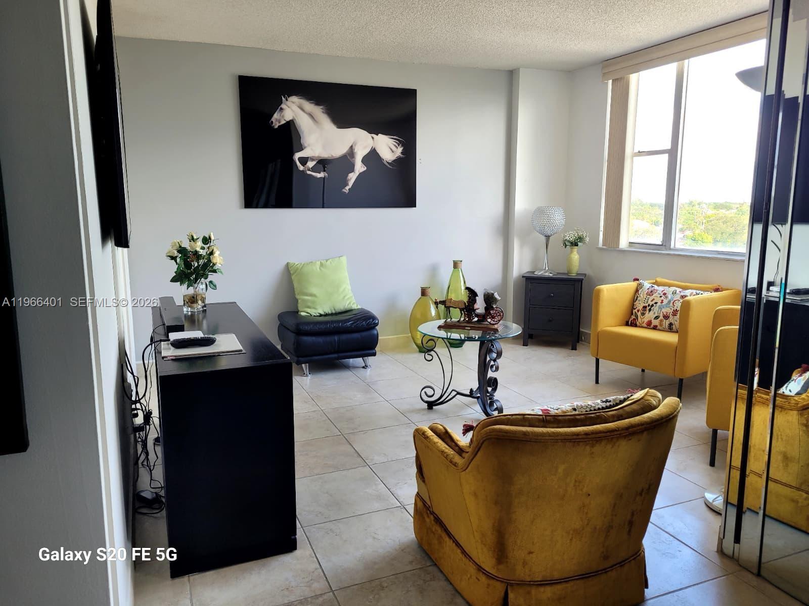 A living room features tiled floors, yellow armchairs, a black console table, and horse artwork — 4001 Hillcrest Dr # 705, Hollywood FL 33021, HOLLYWOOD, FL