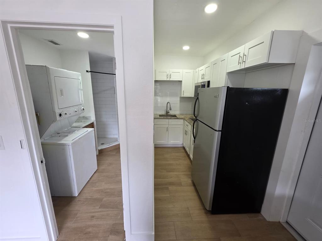 A kitchen with white cabinets and a black refrigerator sits next to a laundry area — 1614 N WASHINGTON AVENUE, CLEARWATER, FL