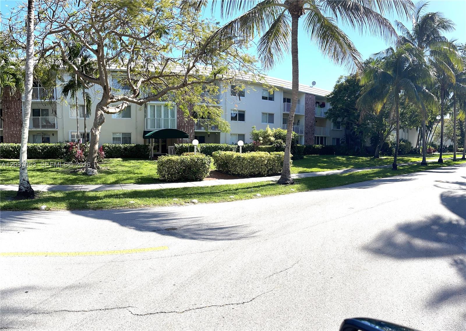A multi-story apartment building with balconies stands behind a lawn and palm trees — 240 Galen Dr # 214, Key Biscayne FL 33149, KEY BISCAYNE, FL