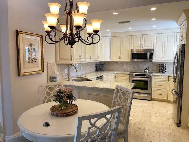 A kitchen with white cabinets, stainless steel appliances, and a round dining table with chairs — 2502 N Fairway Dr Drive N, Jupiter FL 33477, JUPITER, FL