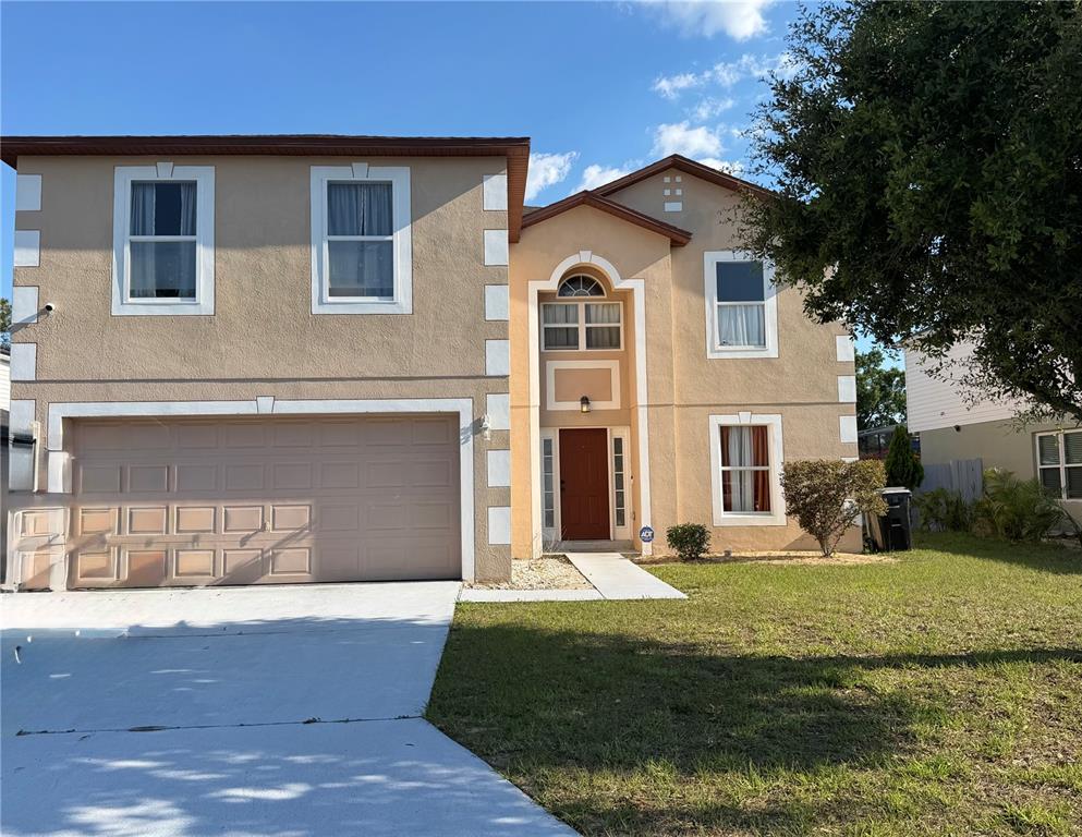 A two-story house with a tan stucco exterior, white trim, and an attached two-car garage — 510 LOBELIA DRIVE, DAVENPORT, FL