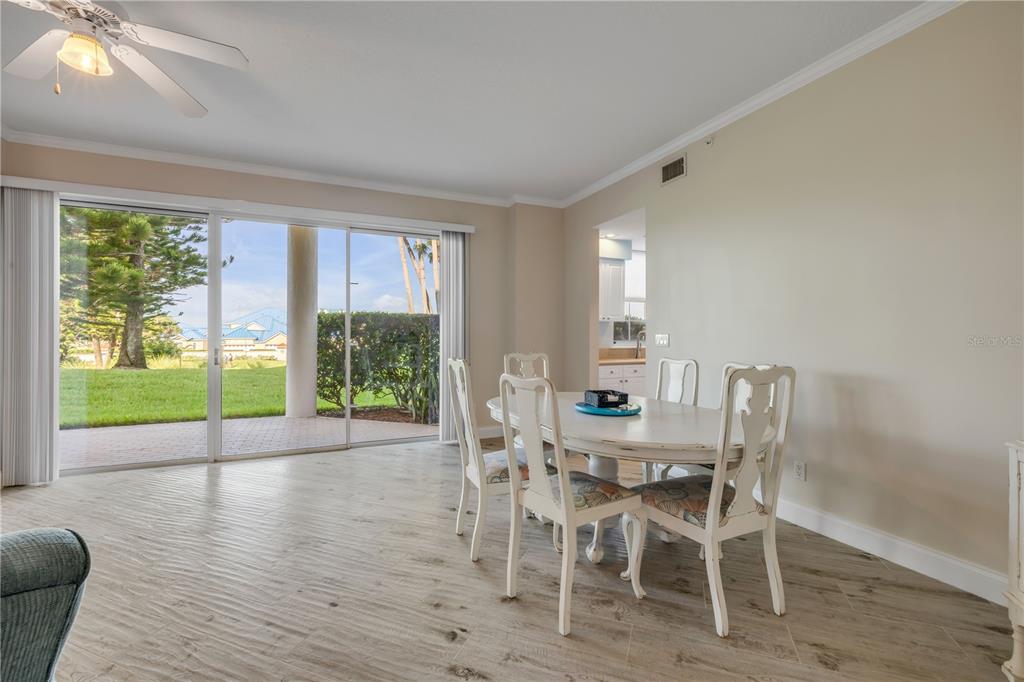 A dining area with a white table and chairs sits beside sliding glass doors — 4650 LINKS VILLAGE DRIVE UNIT B103, PONCE INLET, FL