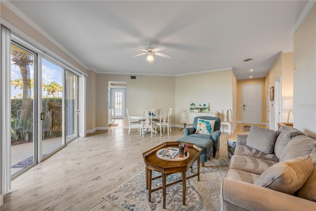 A living room with light wood-look tile floors, a ceiling fan, and sliding glass doors — 4650 LINKS VILLAGE DRIVE UNIT B103, PONCE INLET, FL