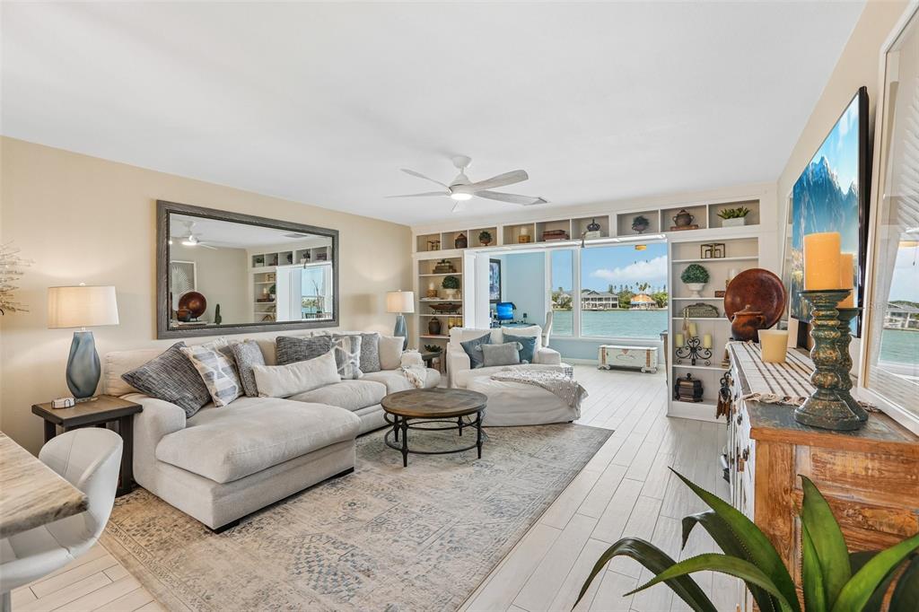 A living room features a sectional sofa, built-in shelving, and a view of the water — 770 ISLAND WAY UNIT N204, CLEARWATER, FL