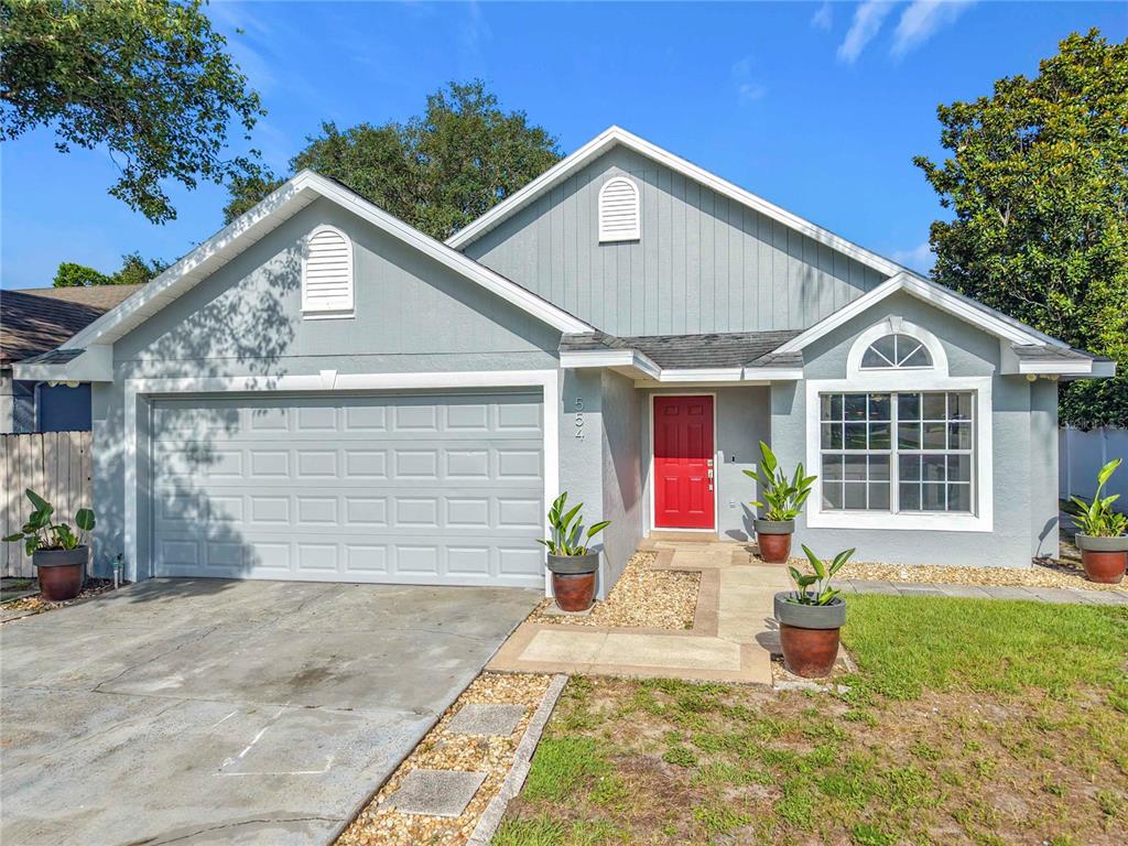 A single-story house with gray siding, a red front door, and a two-car garage — 554 WHITTINGHAM PLACE, LAKE MARY, FL