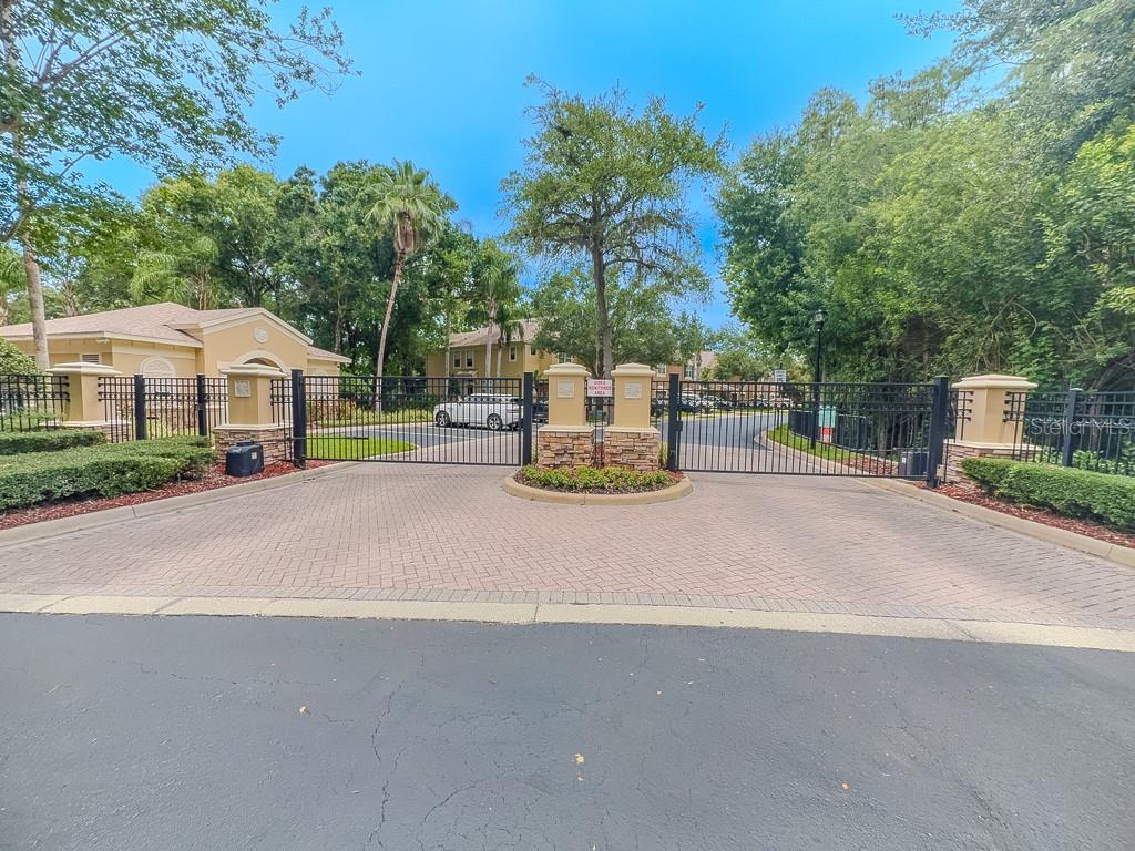 A gated entrance with stone pillars and a brick-paved driveway leads into a residential community — 8505 SANDY BEACH STREET, TAMPA, FL