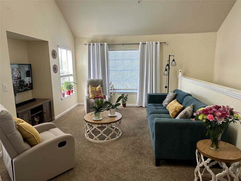 A living room features a blue sofa, two armchairs, a coffee table, and a television — 9005 LEE VISTA BOULEVARD UNIT 1805, ORLANDO, FL