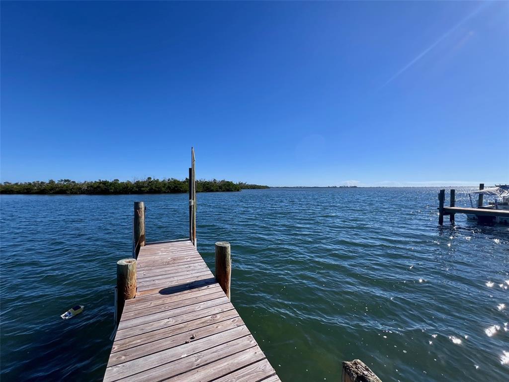 A wooden dock extends into a calm body of water under a clear blue sky — 8142 LITTLE GASPARILLA ISLAND, PLACIDA, FL